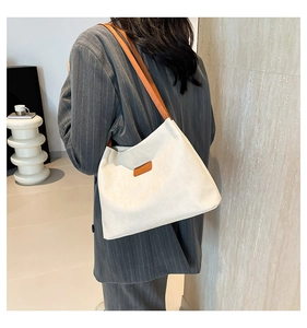 Detail of off-white corduroy tote bag with brown leather straps and brand patch