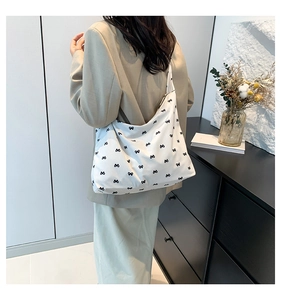 Detail of white canvas tote bag featuring black bow patterns and large storage capacity