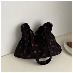 Détail de la texture d'un cabas en velours côtelé noir avec motifs fraises rouges