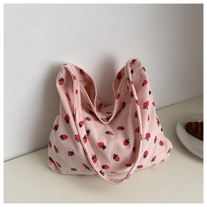 Gros plan du sac cabas en velours côtelé rose avec motif fraise et texture souple