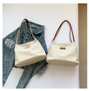 Flat lay of cream canvas tote bags with leather straps and logo patch on denim jacket
