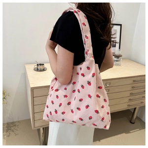 Detailed close-up of pink corduroy tote bag featuring red strawberry pattern and soft texture