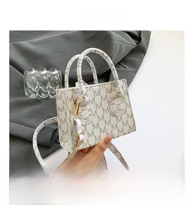 Macro detail of white monogram crossbody bag with gold hardware and M-pattern print