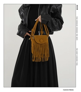 Detail of yellow fringed crossbody bag with round buckle on black leather jacket