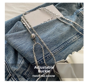 Detail of adjustable silver chain strap with spherical buckle on a white leather bag