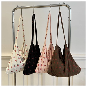 Detailed texture of corduroy tote bags with strawberry prints in four colors on a rack