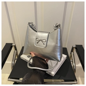 Detail of silver metallic handbag featuring a stylish metal bow buckle and PU leather texture