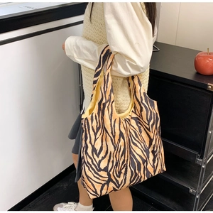 Detail of orange zebra print tote bag shown on model highlighting its large capacity