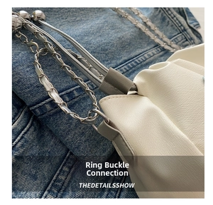 Detail showing the silver metal ring connector and chain strap of the white bucket bag