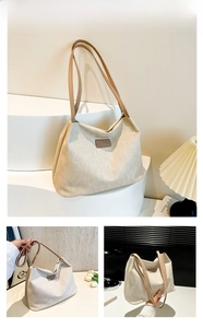Close-up of khaki canvas tote with brown leather strap and logo patch on display
