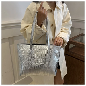 Macro detail of silver tote bag showing realistic crocodile embossed texture on faux leather