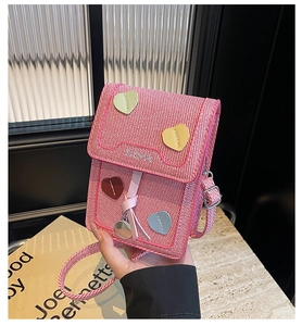 Macro detail of pink knit crossbody phone bag with heart patches and mirror charm
