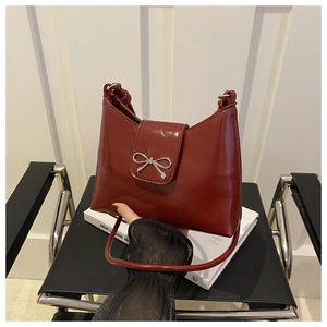 Detailed view of wine red glossy patent leather handbag with metal bow clasp