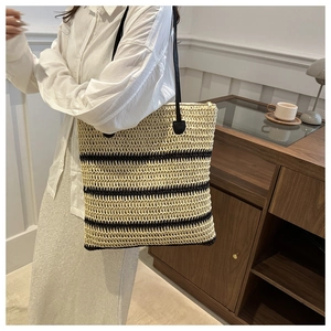Detail of summer woven straw tote bag with black stripes and slender shoulder straps