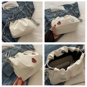 Detail view of white leather bucket bag with colorful 3D heart charms and chain strap