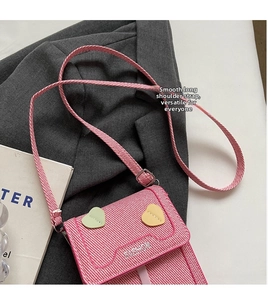 Detailed close-up of pink textured crossbody phone bag with heart appliqués and fashion logo