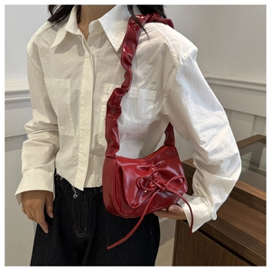 Macro shot of a red bow underarm bag with glossy patent leather and ruched strap