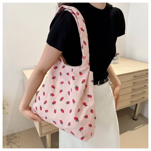 Detail of pink corduroy tote bag with strawberry print shown on model for daily use