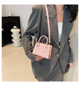 Detailed macro of pink mini handbag with M-pattern monogram and gold metal hardware