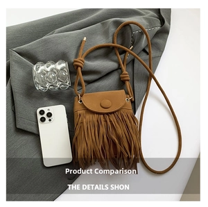 Macro shot of faux suede fringe details and round decorative buckle on a camel crossbody bag