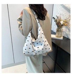 Detailed side view of white crossbody tote bag with black bow print on a model