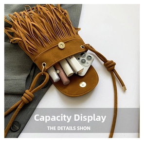 Macro view of brown faux suede fringe bag capacity showing smartphone and lipstick