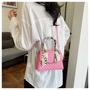Close-up of pink quilted crossbody bag with silk scarf wrapped handle shown on a model
