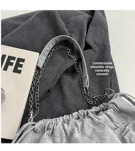 Détail du sac seau plissé métallisé argent avec bandoulière chaîne sur fond gris