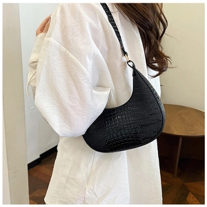 Side view of black faux leather crescent bag with glossy crocodile pattern and silver hardware