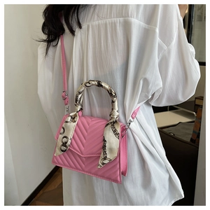 Detailed shot of pink quilted crossbody bag with decorative chain-print silk scarf handle