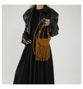 Detail of crossbody bag with fringe tassels and knot strap on black leather jacket