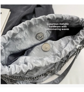 Vue macro du sac seau argenté plissé avec fermoir magnétique et bandoulière en chaîne