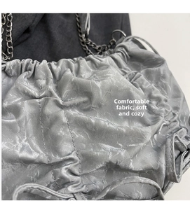 Détail de la texture plissée gris argenté et chaîne en métal noir sur le sac seau