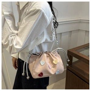 Detail of pink canvas drawstring bucket bag with colorful heart patches and silver chain