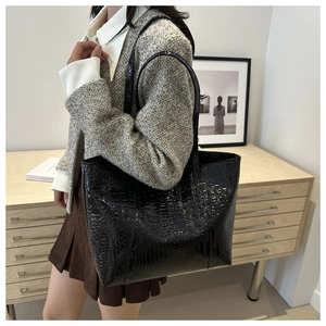 Close-up of a large black crocodile pattern tote bag showing glossy texture and handles