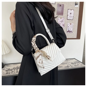 Quilted white crossbody bag with silk scarf wrapped handle shown in a lifestyle setting