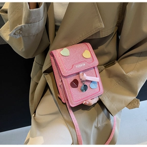 Detail of pink fabric crossbody bag featuring multi-color heart patches and FASHION text