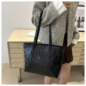 Close-up of black crocodile textured leather tote bag on model for elegant daily look