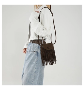 Detailed view of bohemian brown suede shoulder bag with long fringes worn by a model