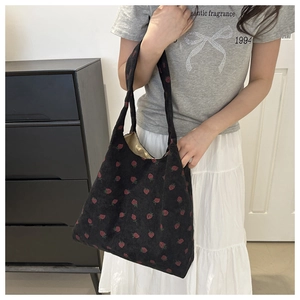 Detail of black corduroy tote bag featuring strawberry print and comfortable handles