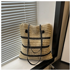 Gros plan du sac cabas tissé à rayures avec anses en cuir noir et détails de zip dorés