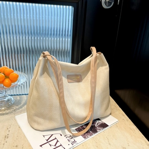 Large beige canvas tote bag with brown leather straps and textured woven material