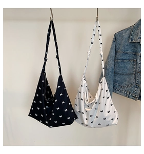 Close-up of black and white floral canvas hobo bags featuring decorative shoulder knots