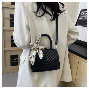 Detail of black V-quilted leather crossbody bag decorated with an elegant patterned silk scarf