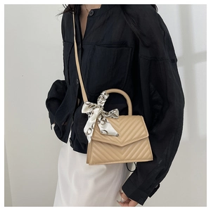Detail view of beige quilted handbag featuring V-shape texture and decorative silk scarf
