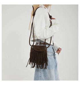 Detail of dark brown fringe crossbody bag with suede texture and boho tassel design