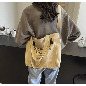 Large beige canvas tote bag shown worn over the shoulder for student style and daily use