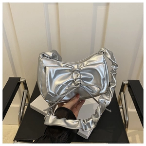 Close-up of metallic silver crescent bag featuring a large bow and ruffled strap detail