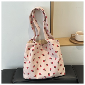 Close-up of pink corduroy tote bag with strawberry prints and soft fabric texture
