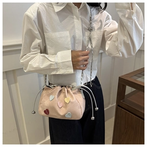 Dettaglio di una borsa rosa chiaro con coulisse e toppe in pelle colorate a forma di cuore